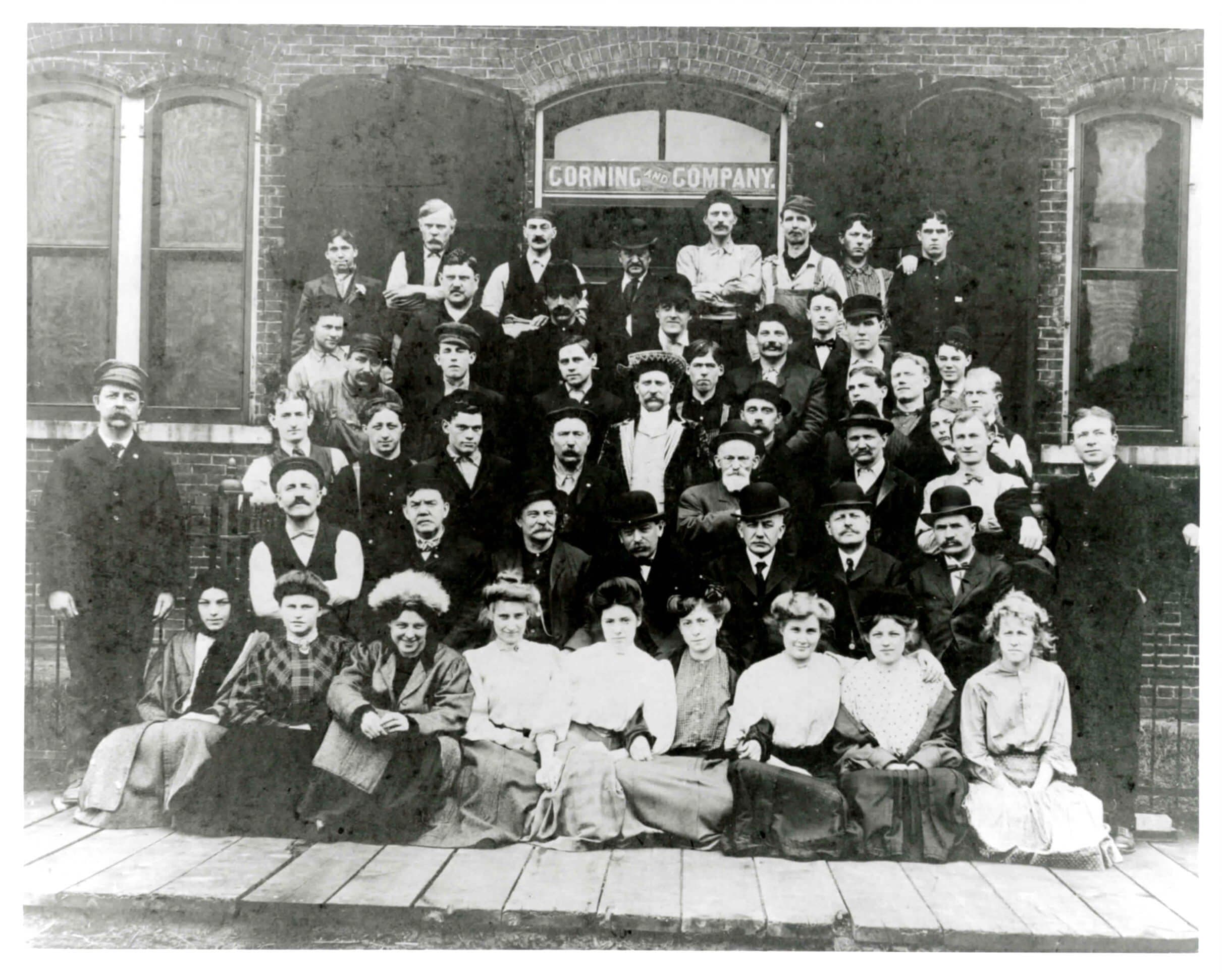 The Corning & Company workforce posed outside the distillery under the company sign, circa 1906